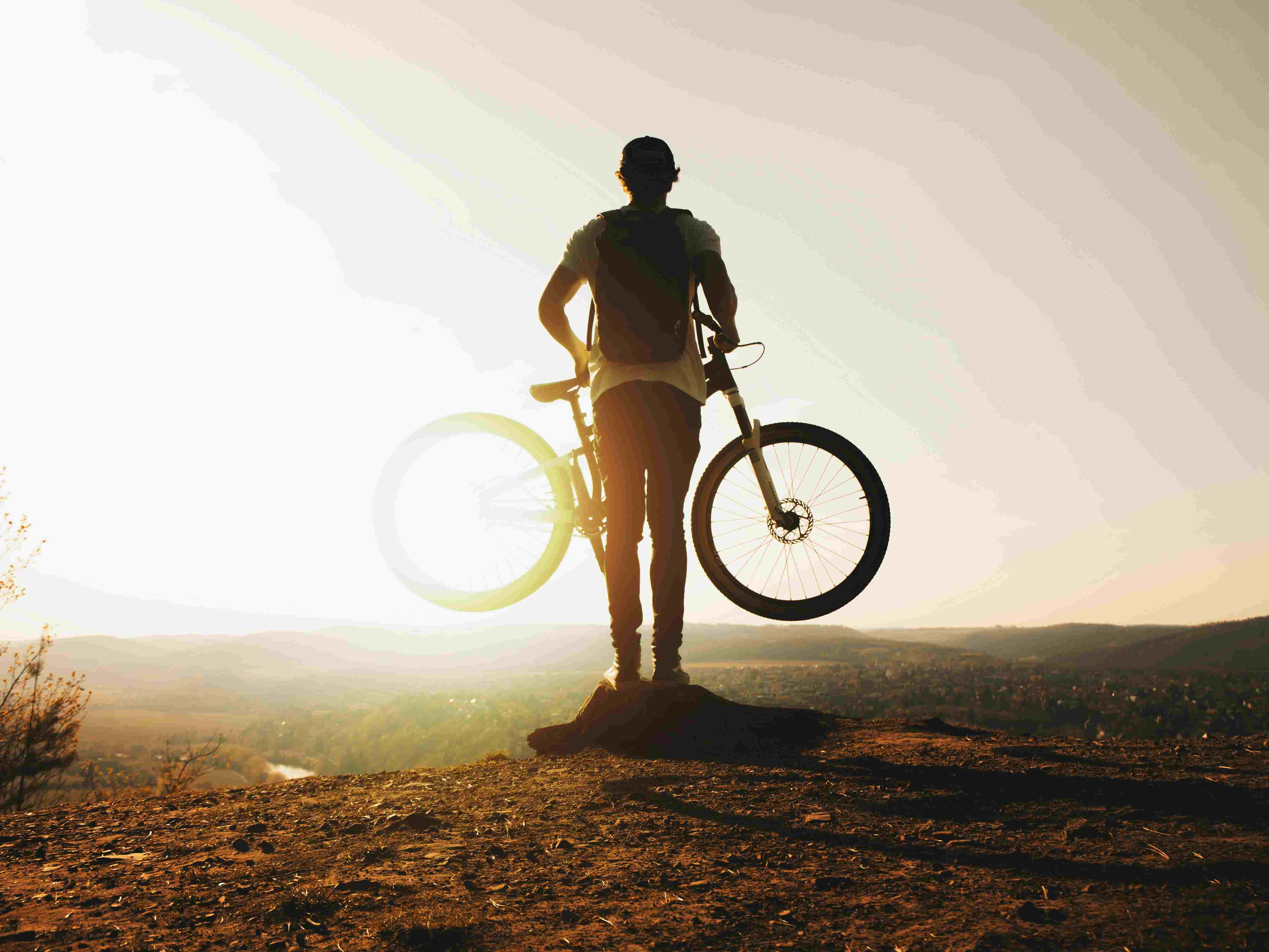 Man holding bike looking into sunrise