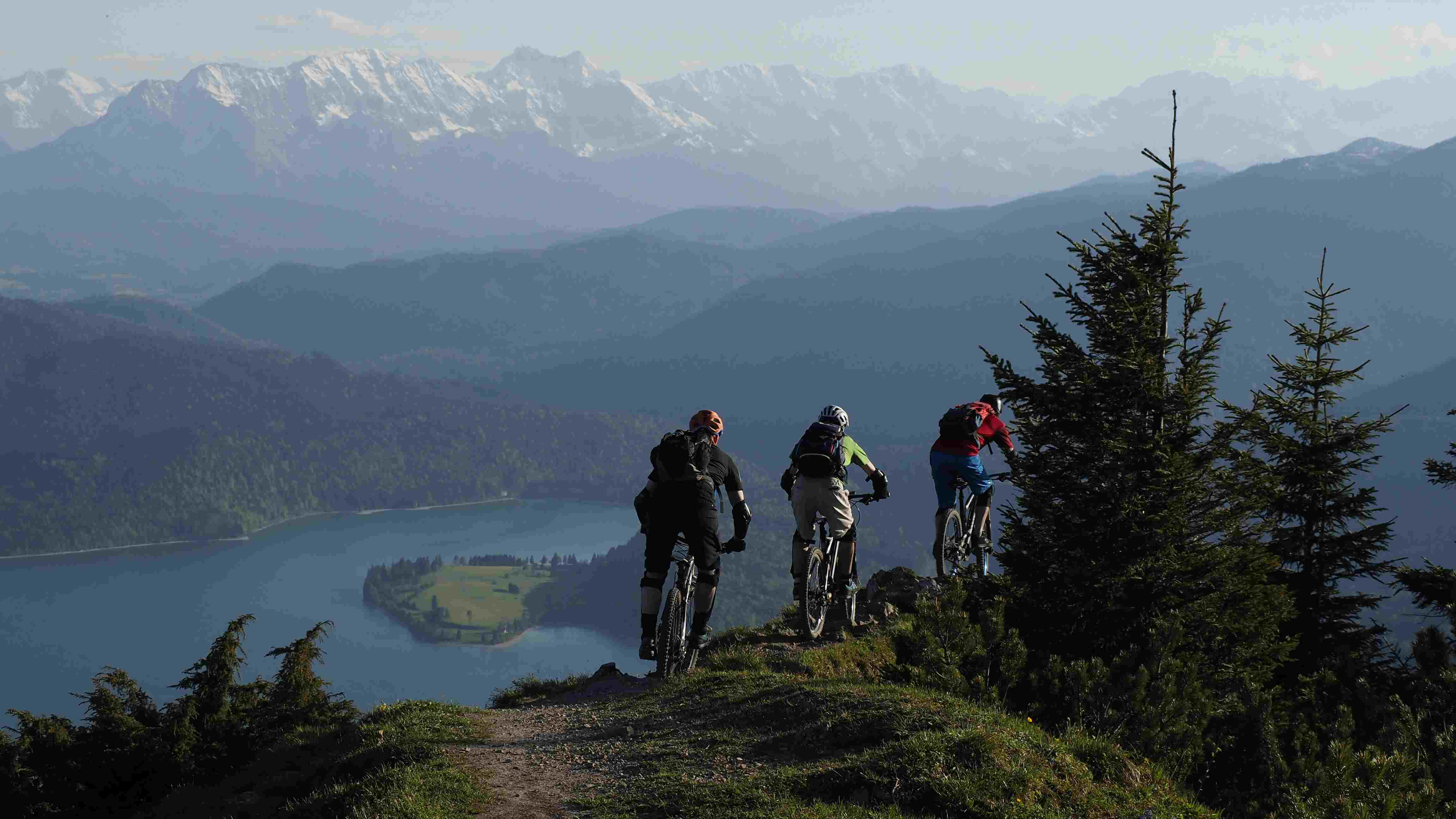 Three cyclists on mountain summit above a loch